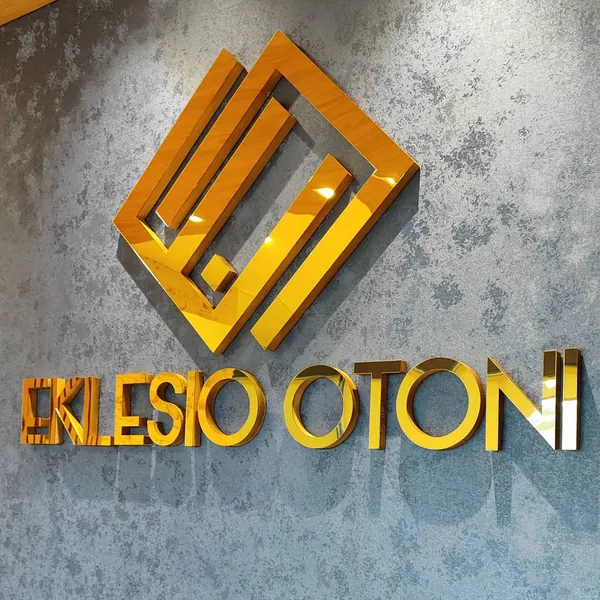 Logo de Eklesio Otoni em acrílico espelhado dourado, com todos os traços inteiros
